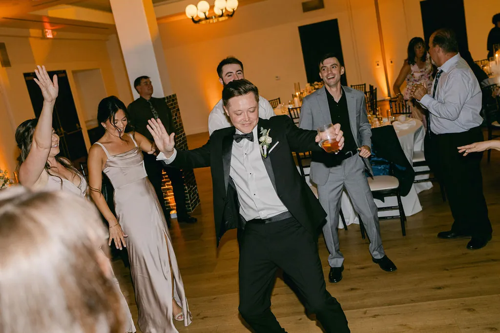 Guests dancing with arms raised under warm venue lighting