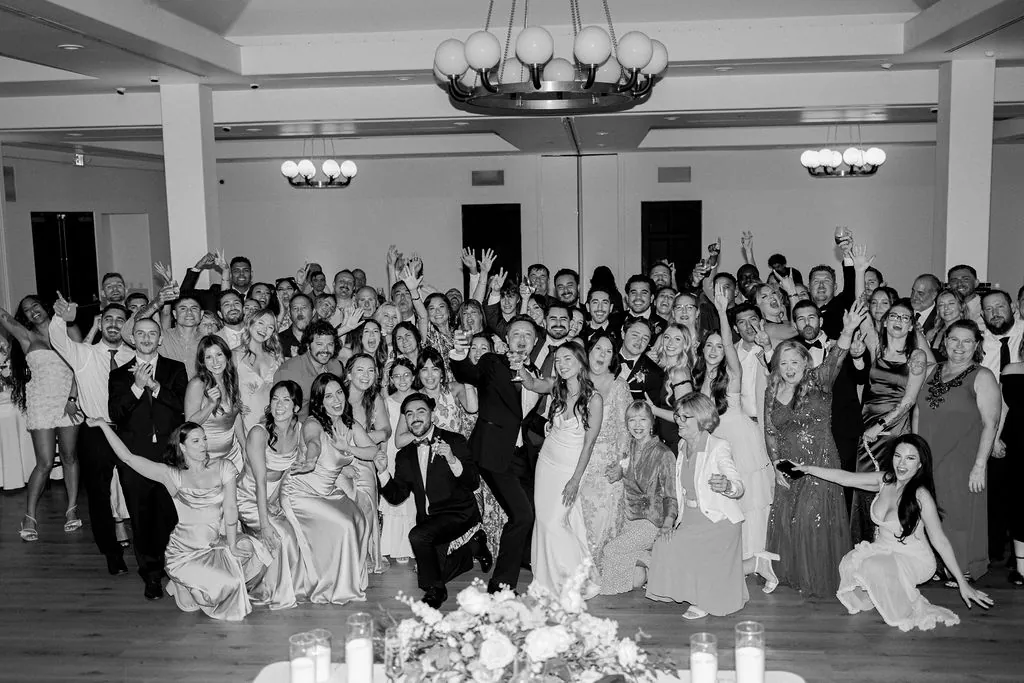 Wedding guests packed onto the dance floor beneath a chandelier