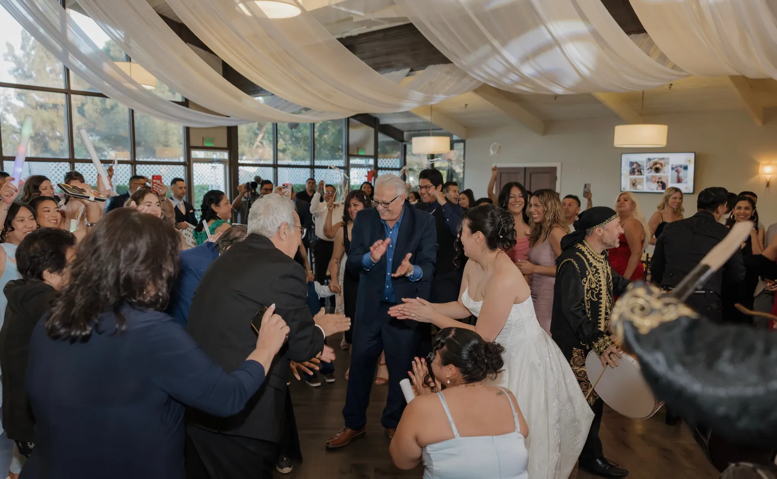 Wedding guests and the bride clapping in a circle on a packed dance floor