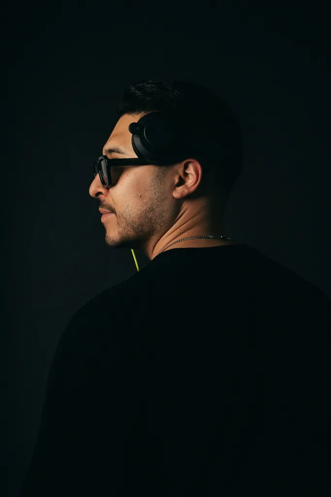 DJ Lowso in profile wearing headphones and sunglasses against a black background